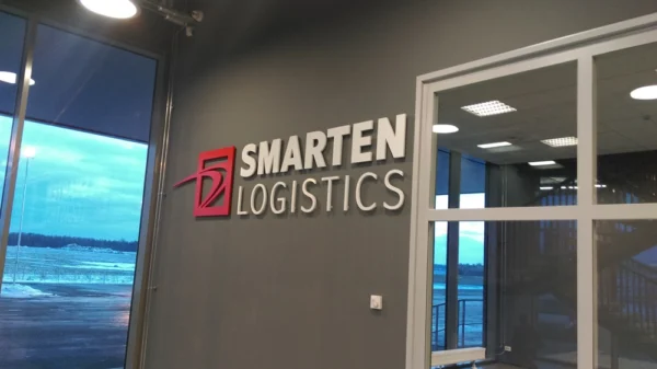 Smarten Logistics mahulised tähed ja punane logo hallil seinal kontoris