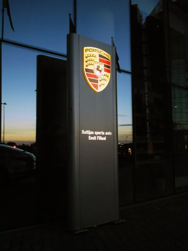 Porsche valgustatud reklaampost autoesinduse sissepääsu ees õhtuhämaruses