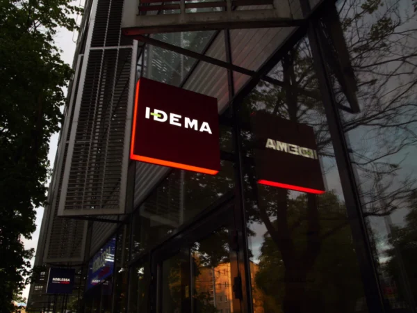 IDEMA punased külgmised valguskastid sissepääsu kohal õhtuhämaruses