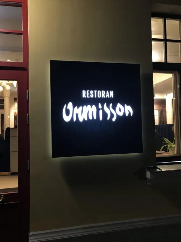Restoran Urumissoni valgustatud silt maja fassaadil õhtuhämaruses