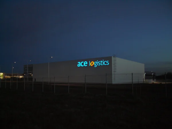 Ace logistics valgustatud logo lao fassaadil õhtuhämaruses