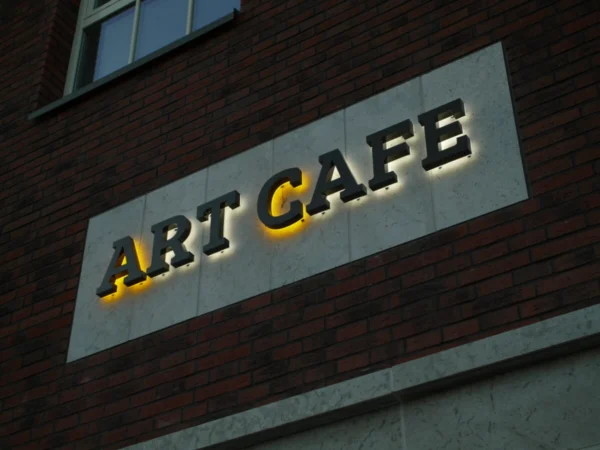 Art Cafe taustvalgustatud tähed valgel paneelil telliskivifassaadil