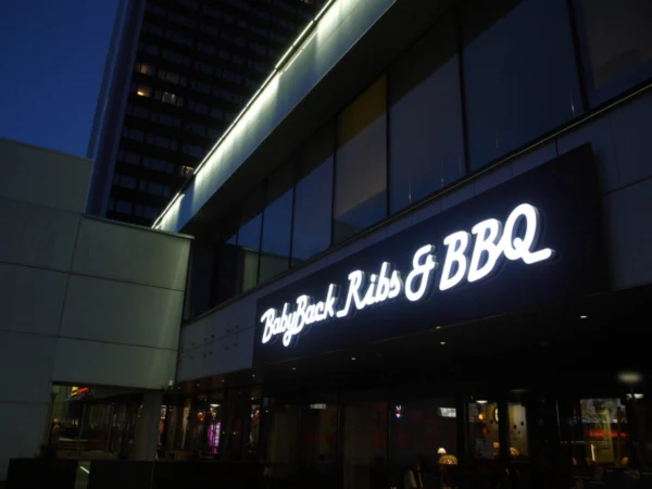 BabyBack Ribs & BBQ valgustatud skripttekst restorani fassaadil õhtuhämaruses