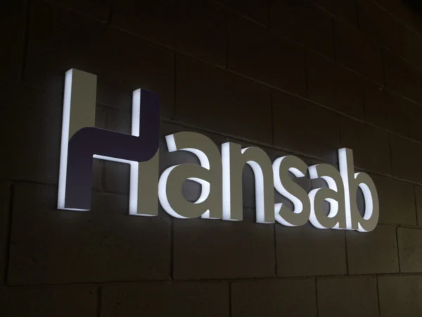 Hansab valgustatud logo tumedal telliskiviseinal