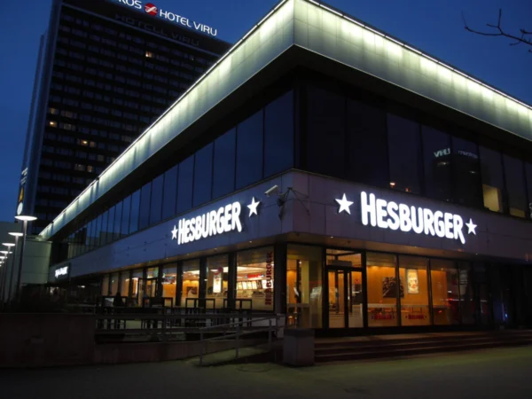 Hesburgeri valgustatud logo tähtedega nurgahoone fassaadil Viru väljaku ääres