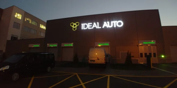 Ideal Auto valgustatud logo ja tekst autohoolduskeskuse fassaadil õhtuhämaruses