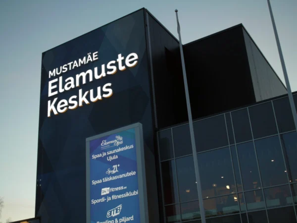 Mustamäe Elamuste Keskuse valgustatud logo spordi- ja vabaajakeskuse fassaadinurgal