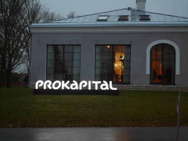 Prokapitali valgustatud logo maapinnal ajaloolise kontorihoone ees õhtuhämaruses