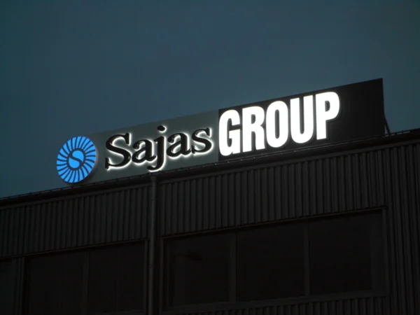 Sajas Groupi valgustatud logo tööstushoone katusel õhtuhämaruses