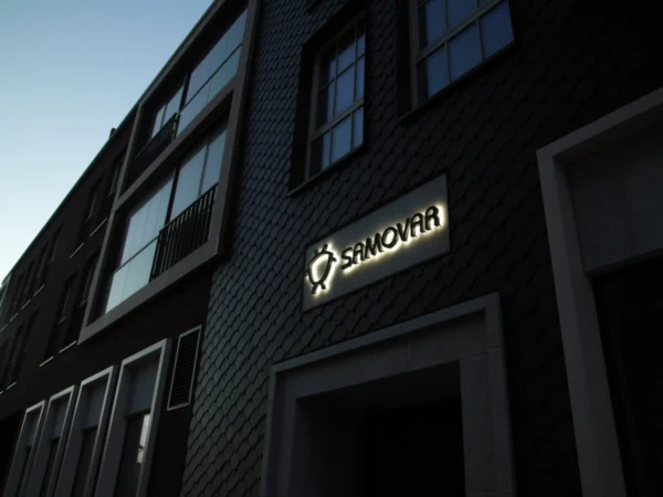 Samovari valgustatud logo kilpkatusega maja fassaadil õhtuhämaruses